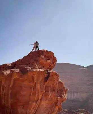 two people standing on top of a mountain at مخيم نجوم رم in Maḩaţţat Dīsah