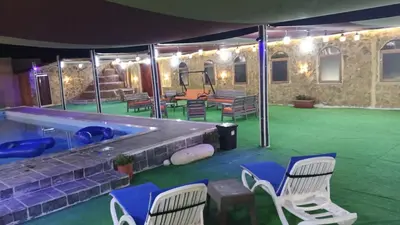 a room with chairs and a pool with a green floor at شاليهات تلال اشتفينا in Ajloun