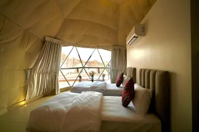two beds in a room with a large window at Terra Nova Camp in Wadi Rum