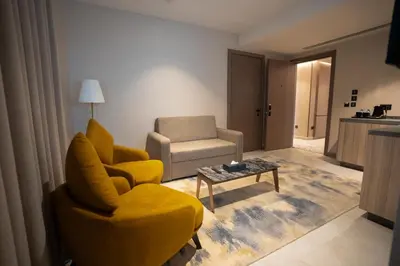 a living room with a yellow chair and a table at Golden Suites Hotel in Amman