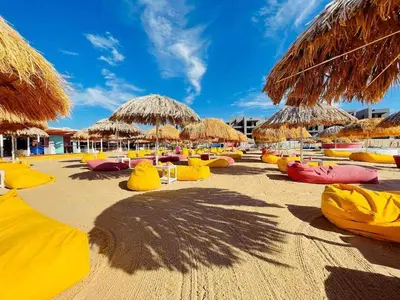 a beach with straw umbrellas and kayaks on it at Brand new modern apartment in Ayla Golf residence in Aqaba