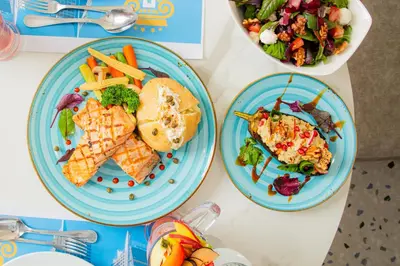 a table with three plates of food and a salad at Armada Avenue Hotel Amman in Amman
