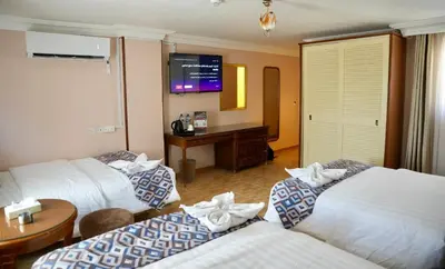 a hotel room with three beds and a television at Mass Plaza Hotel in Aqaba