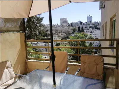 a table and chairs on a balcony with an umbrella at Humble house in Amman