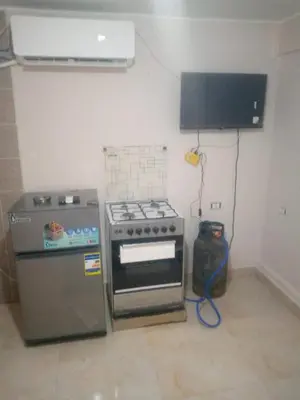 a kitchen with a stove and a refrigerator and a television at يرموك هاوس in Aş Şarīḩ