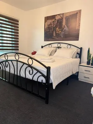 a bedroom with a black bed and a painting on the wall at Beit Ahlam Quiet Duplex Villa with Terrace and Scenic View near Umm Qais Ruins in Um Qeis