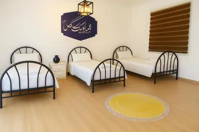 a room with three beds and a clock on the wall at Beit Ahlam Quiet Duplex Villa with Terrace and Scenic View near Umm Qais Ruins in Um Qeis