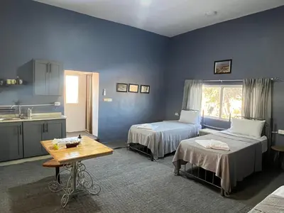 a blue room with two beds and a table at Beit Philodemus 2 in Um Qeis