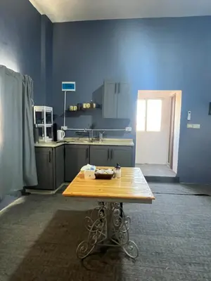 a blue kitchen with a wooden table in it at Beit Philodemus 2 in Um Qeis