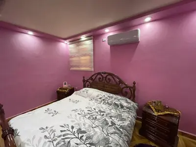 a bedroom with purple walls with a bed and two night stands at Luxury couple room in irbid in Irbid