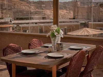 a wooden table with chairs and a vase of flowers at Petra Jewel Hotel in Wadi Musa