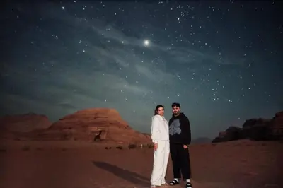 a man and a woman standing in the desert at night at Kinda Rum Luxury Camp in Wadi Rum