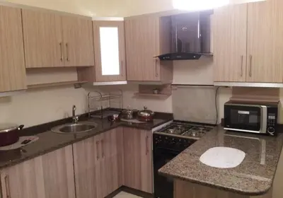a kitchen with wooden cabinets and a sink and a microwave at Family apartment in Abdoun Al Janobi in Amman