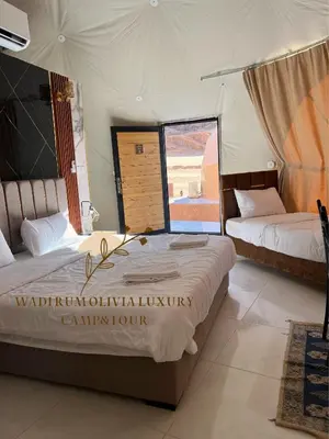 two beds in a room with a view of the desert at WADI RUM OLIVIA lUXURY CAMP & TOUR in Wadi Rum
