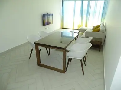 a living room with a glass table and white chairs at B12 beach apartment Ayla in Al Jafr
