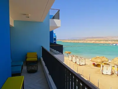 a balcony with a beach with chairs and umbrellas at B12 beach apartment Ayla in Al Jafr