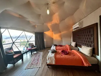 a bedroom with a large bed and a large window at Luxury diamond camp in Wadi Rum