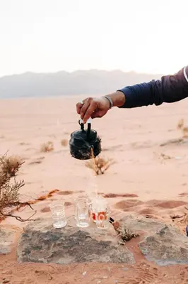 a person is pouring drinks into glasses in the desert at Luxury diamond camp in Wadi Rum