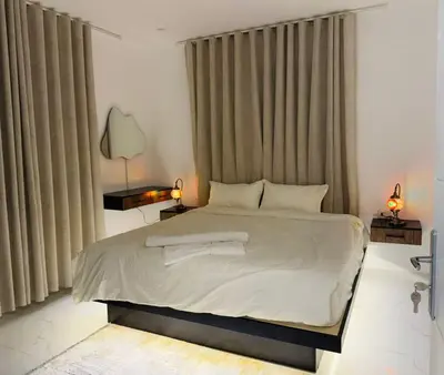 a bedroom with a large white bed with curtains at Beit Ahlan Suites 8 in Amman