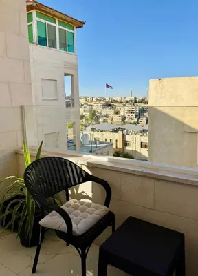 a chair sitting on a balcony with a view of a city at Beit Ahlan Suites 8 in Amman