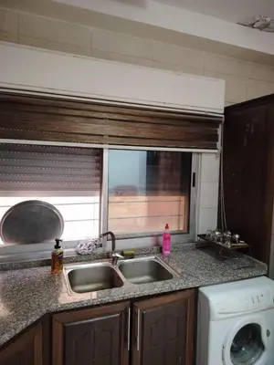 a kitchen counter with a sink and a window at mraco apartment in Amman