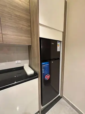 a small kitchen with a refrigerator and a microwave at Charming Amman Apartment with Modern furnis in Amman