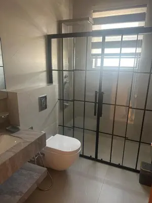 a bathroom with a toilet and a glass shower at Apartment in dergbar in Amman