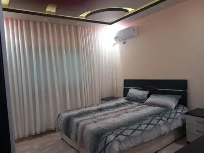 a bedroom with a bed and a window with curtains at Amman Central Elegant Apartment in Amman