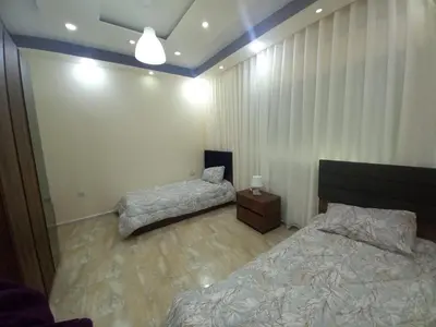 a bedroom with two beds and a night stand at Amman Central Elegant Apartment in Amman