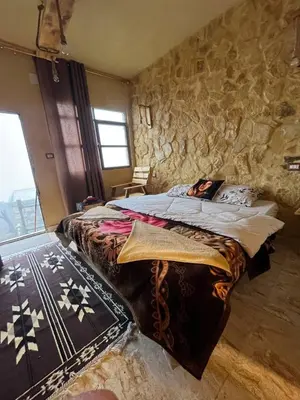 a bedroom with a large bed in a stone wall at Friends of Dana Hotel in Dana
