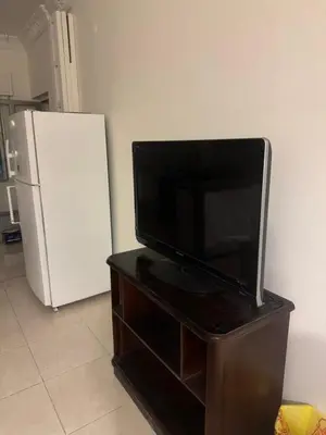 a flat screen tv sitting on a stand next to a refrigerator at الاردن عمان الجاردنز in Amman