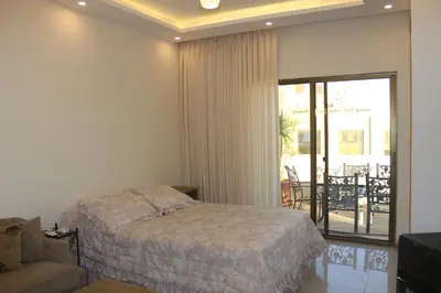 a bedroom with a bed and a couch and a balcony at Private Studio in Amman