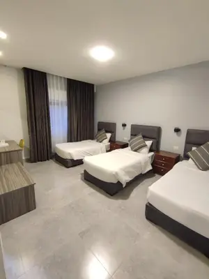 a hotel room with two beds and two tables at Black Iris Hotel in Madaba