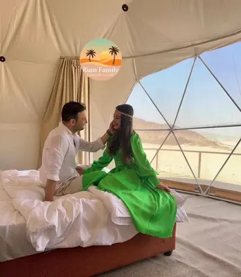 a man and woman sitting on a bed in a tent at RUM fAMILY lUXURY CAMP in Wadi Rum