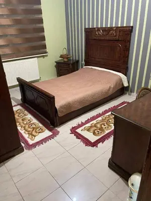 a bedroom with a bed and two rugs on the floor at Nargges House in Al Salt