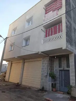 a building with two garage doors and a balcony at Nargges House in Al Salt