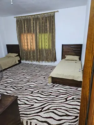 a bedroom with two beds and a rug at غصن الزيتون in Ajloun