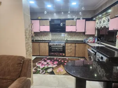 a kitchen with pink cabinets and a table and a rug at A big Family nice sunset flat in Amman