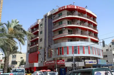 a tall apartment building with a red at CITYRISEHOTELINAMMAn in Al Jafr