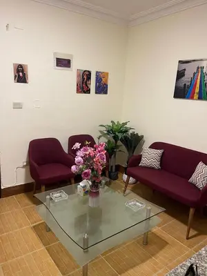 a living room with two couches and a glass table with flowers at Furnished one bedroom apartment in Amman