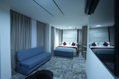 a hotel room with two beds and a blue couch at Roya Downtown Boutique Hotel in Amman