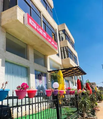 a building with flowers in front of it at Althemar Hotel Ajloun -Jordan By Enala Hotels Group in Ajloun