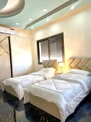 two beds in a bedroom with a window at Luxury 2 Bedroom Apartment in Amman