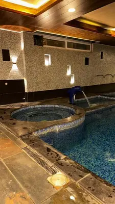 a swimming pool in a building with a water fountain at Al-Amaari Gardens Compound 3092 in Irbid