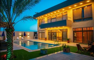 a house with a swimming pool and a palm tree at Sunshine Chalet in Shūnat Nimrīn