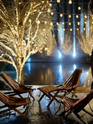 two chairs sitting in front of a tree with lights at Sunshine Chalet in Shūnat Nimrīn