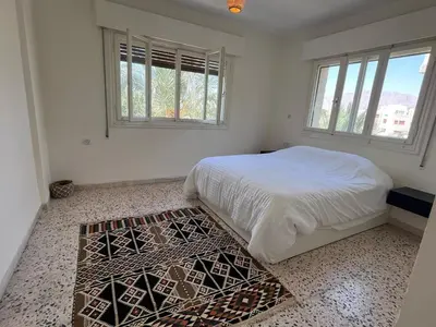 a white bedroom with a bed and a rug at White castle in Aqaba