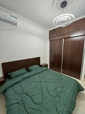 a bedroom with a bed with a green comforter at stay by university of Jordan in Amman
