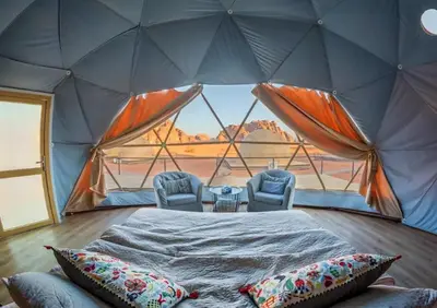 a tent with two chairs and a bed in a room at Celestial Mirage Camp in Wadi Rum