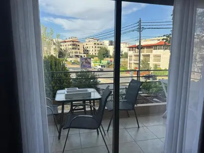 a balcony with a table and chairs and a view of a city at Glow and Grace in Abdoun Best location in Amman